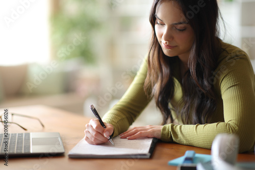Student learning taking notes on a wooden table at home