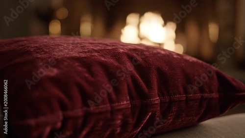 Luxurious burgundy velvet pillow on sofa with warm blurred background