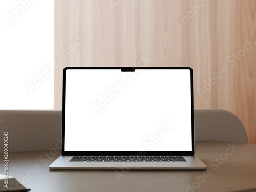 Laptop mockup against light wood wall background in a bright minimalist room.