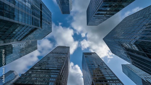 Tall skyscrapers stand under a cloudy blue sky in the city.