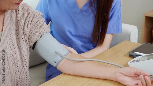 Asian woman nurse measuring blood pressure senior patient, medical checking for hypertension monitoring, caregiver support elderly woman with arterial blood pressure device, routine health checkup.