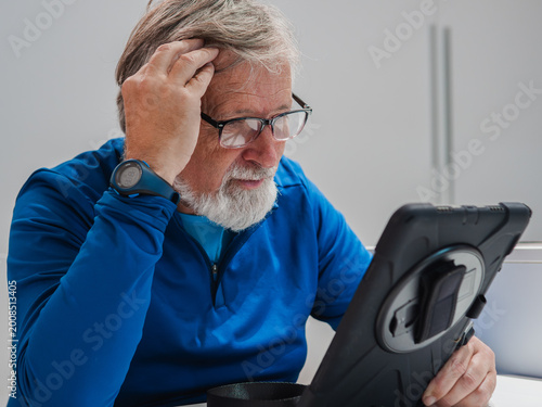 Elderly man exploring technology with focused expression indoors