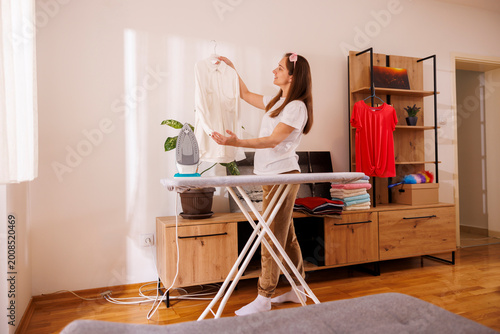 Woman ironing fresh clean clothes while doing housework