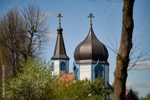 Tableau sur toile Onion domes and crosses of the Orthodox Church of the Dormition of the Mother of God peaking above trees, Wojnowo, Masuria, Poland, Europe