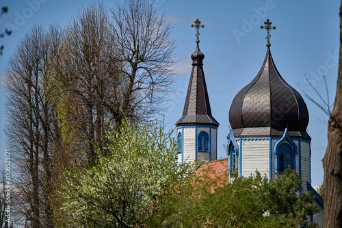 Valokuva Wooden onion domes and spire of the Orthodox Church of the Dormition of the Mother of God framed by trees, Wojnowo, Masuria, Poland, Europe