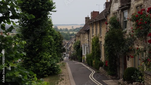 Sunny quiet uphill village street lined with stone houses and geraniums