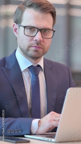 Businessman Looking at Camera while using Laptop