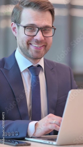 Businessman with Laptop Smiling at Camera