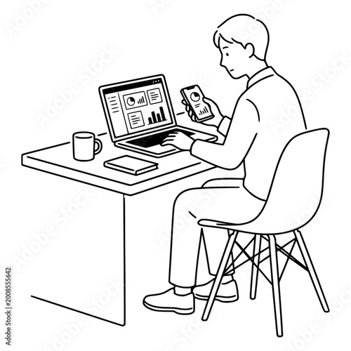 Businessman works on his laptop and checks data on a smartphone while sitting at a desk in a modern home office environment.