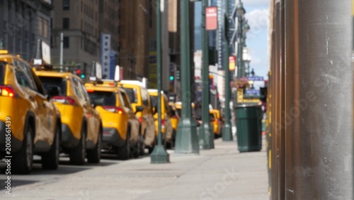 Manhattan Midtown street New York City, United States. Defocused row of yellow taxi cars. Many taxi cabs in line on 8th avenue near Penn Station. Taxi queue, urban road traffic, passenger transport.