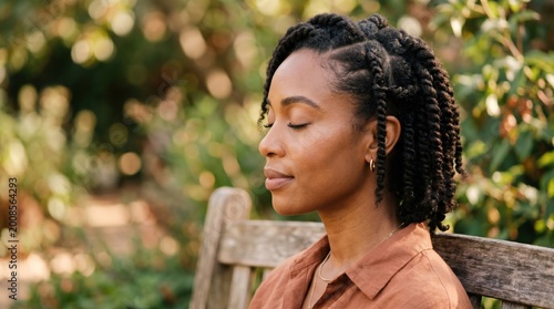 Black woman meditating outdoors with eyes closed on a wooden bench surrounded by greenery african american hair braids