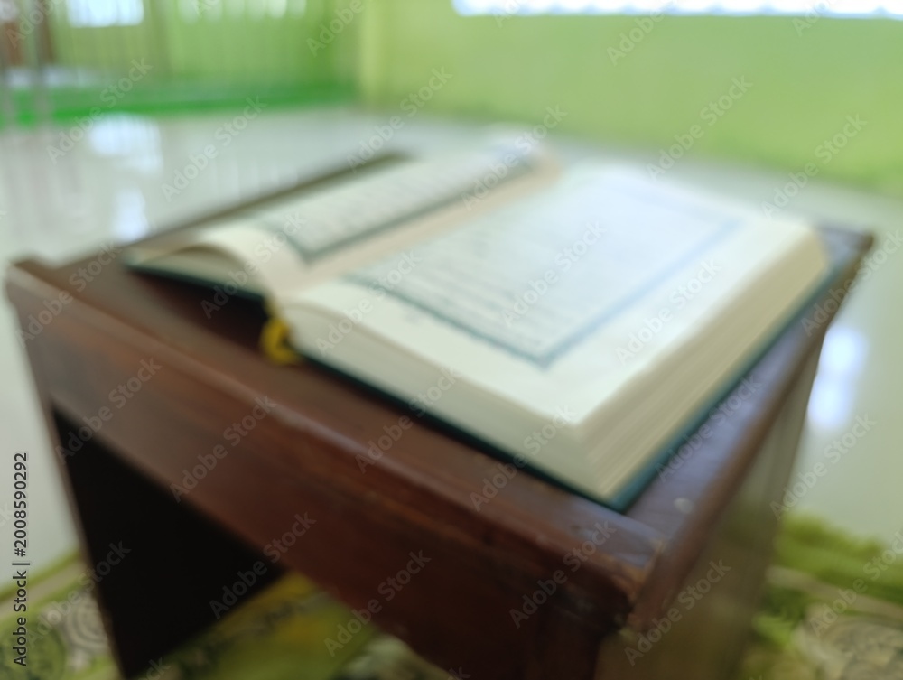 Obraz premium Open Holy Quran on a wooden desk inside a peaceful mosque room