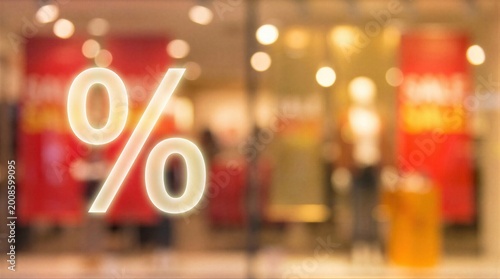 Percent sign on glass shop window. Concept of seasonal sale and retail discount. Marketing promotion for e-commerce and shopping event. Blurred store background with interior lighting.