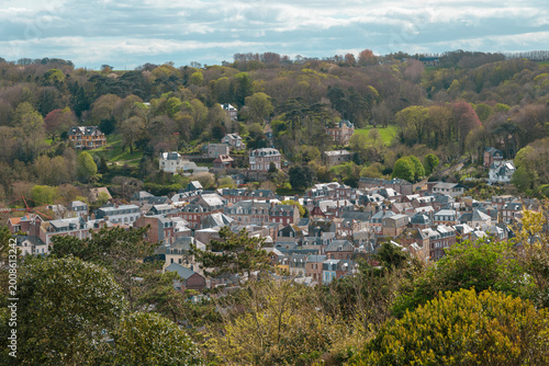 View of a picturesque town nestled among lush green hills during a cloudy spring day