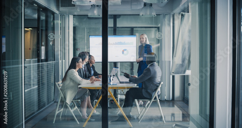 Business Team Meets in a Glass Conference Room to Review Digital Dashboards, Discuss Performance Metrics, Align Strategy, and Plan Key Projects, Focusing on Revenue Growth, Customer Results