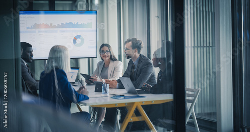 Business Team Meets in a Glass Conference Room to Review Dashboards, Discuss Financial Results, Set Revenue Targets, and Plan Strategy, Using Laptops and Tablets to Analyze Data, Share Insights