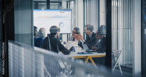 Konstfotografi Business Leaders Sit Around a Conference Table Reviewing Charts on a Large Scree