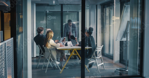 Foto Business Manager Leads a Focused Meeting in a Glass Conference Room, Guiding Col