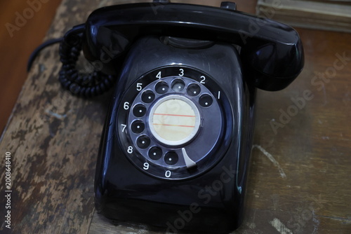 Bild auf Leinwand A vintage black rotary dial telephone on a wooden table.