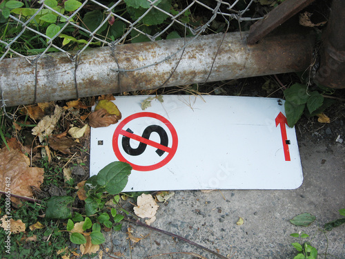 No Stopping sign with a black S encircled by a red circle and red slash, removed from the pole and lying on the ground