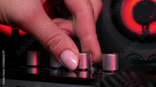 Sound engineer hands adjusting knobs and faders on audio mixer in recording studio.
