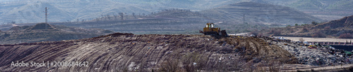 Photos Bulldozer working in an open-air landfill waste site