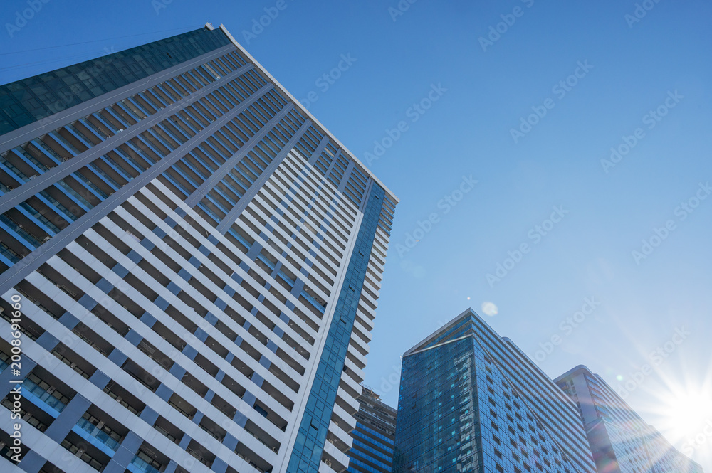 Fototapeta premium Modern high-rise residential buildings with glass facades against a clear blue sky.