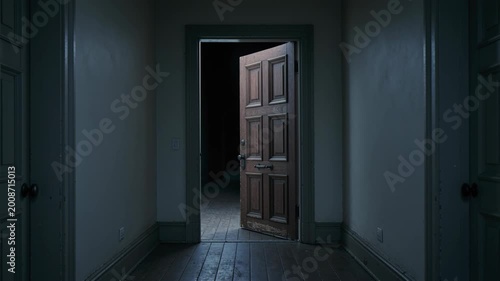 Old wooden door opening slowly in dark hallway, revealing a mysterious path to an unknown room. Creepy ghost house with long corridor.