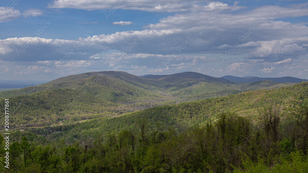 Fototapeta premium Rolling Mountain Landscape with Forested Hills and Cloudy Sky Panorama