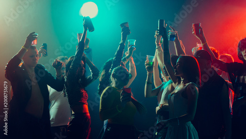 Photography Group of diverse people partying, raising cups, colorful lights