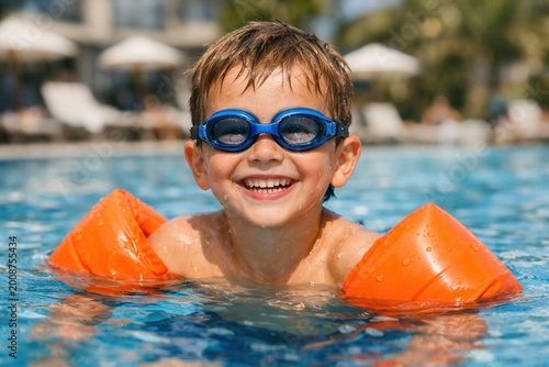 Happy child swimming in pool with goggles and arm float enjoying summer vacation fun water activity