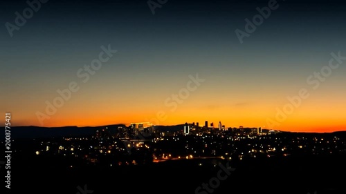 Blurred city lights glow against a vibrant sunset sky