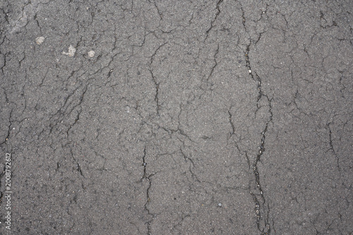 Cracked asphalt texture background with weathered grey pavement surface in city street