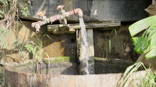 Water flowing from a tank pipe into a concrete basin on a farm