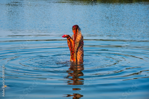 Traditionally dressed Indian woman pray into the river on Chhat Puja Festival.