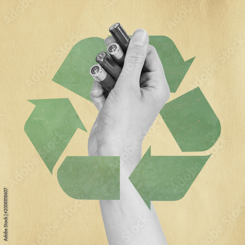 Hand holding aa or aaa batteries over a green recycling symbol on a textured background