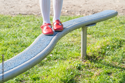 Quadro su tela Child walking balance beam in park, Little girl balancing outdoor equipment, gre