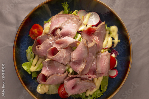 Foto Roast beef salad with peppery arugula chef plated thinly sliced roast beef, cher