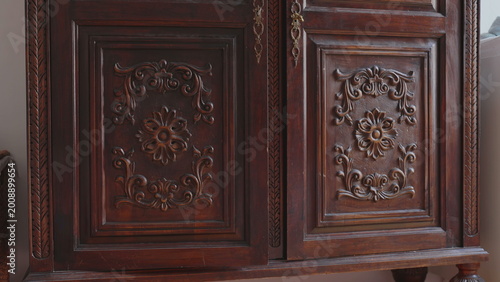 Photos Close-up of vintage wooden cabinet with ornate carved floral patterns, detailed