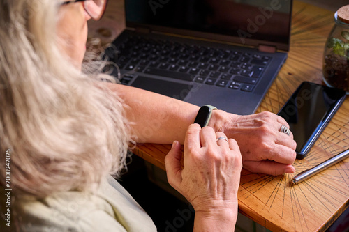 Elderly woman using a fitness tracker at home