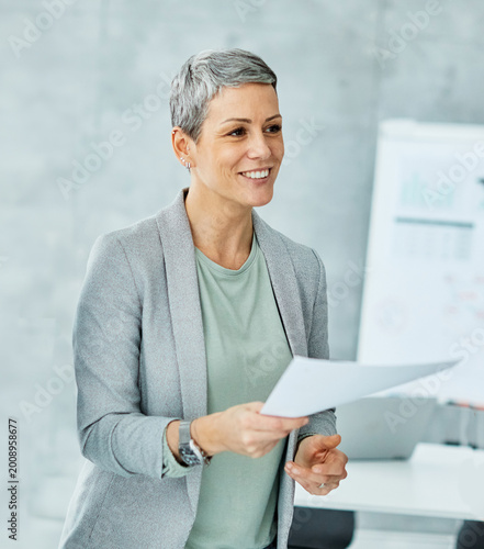 portrait of a smiling young businesswoman doing paperwork and passing document or a contract in the office
