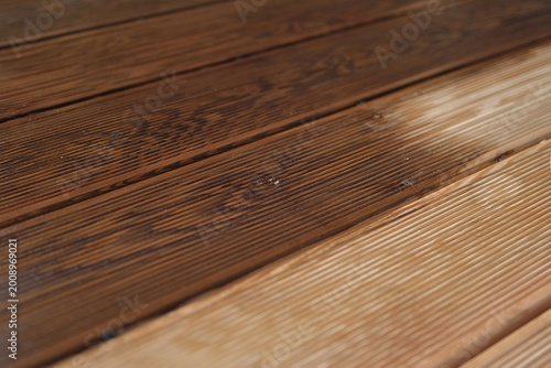 Brown oil for protection of wood by staining. Painting a larch for protecting and pests. Woodworker applying finish to terrace deck board. Repairman varnishing with brush wooden plank floor surface.