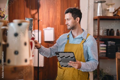 Fotografi Coffee shop worker using tablet in warm interior