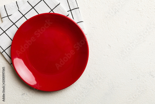Top view on colored background empty round red plate on tablecloth for food. Empty dish on napkin with space for your design