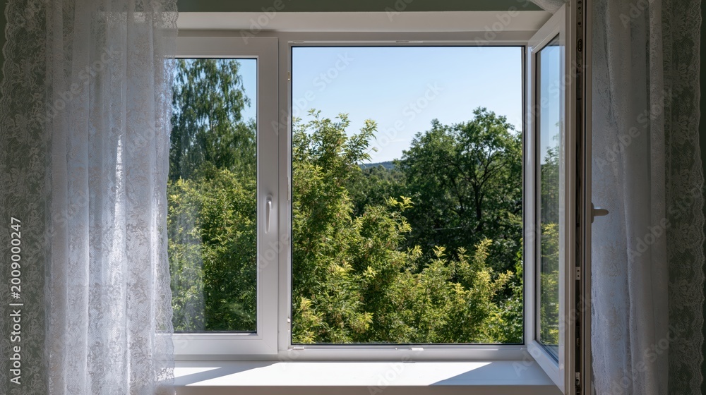 Fototapeta premium Inviting opened white plastic window with lace curtains and a vibrant green tree view under summer sunlight.