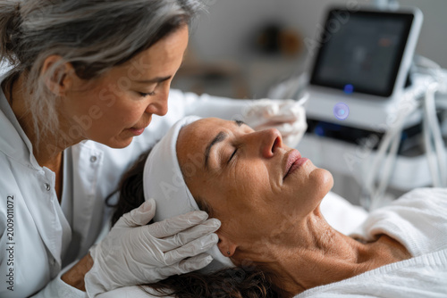 In this image, a woman enjoys a luxurious facial treatment aimed at promoting glowing skin, emphasizing the calming environment and expert care provided by a skincare professional.
