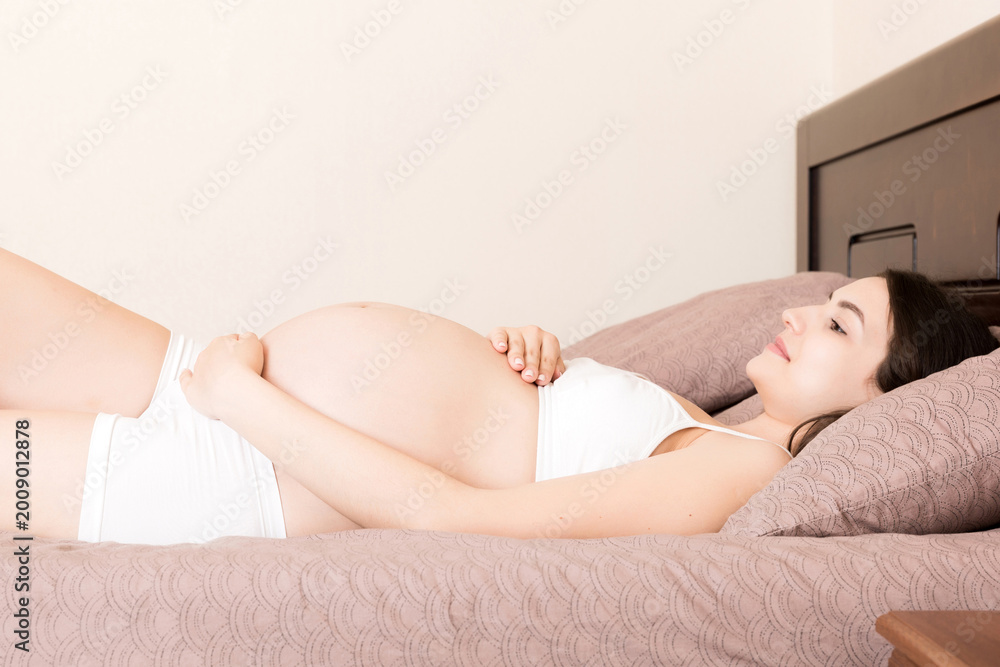 Obraz premium beautiful young pregnant woman lying in bed, top view. the girl suffers from the fact that her husband left her