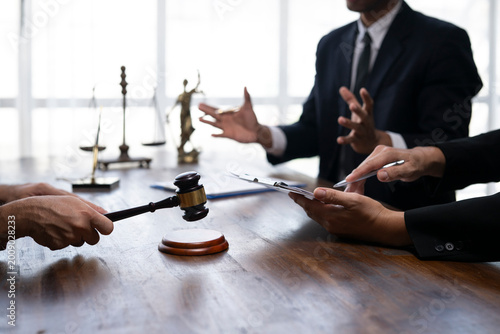 Photos Judge holding gavel during trial in courtroom discussing with lawyer and client