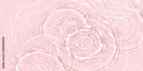 Photos Pink water ripples on a liquid surface with soft circular waves and light reflec