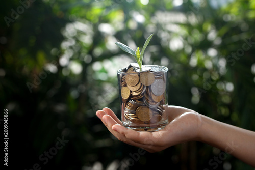 Investment Growth Concept - Hand Holding Coin Jar with Plant Sprout for Retirement Savings and Financial Planning